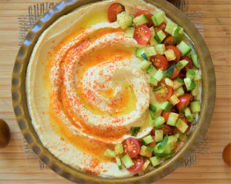 Hummus garnished with olive oil, smoked paprika and vegetablest