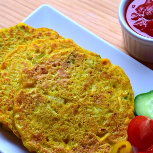Zucchini and corn semolina pancakes served with vegetables and spicy sauce