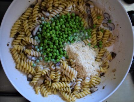 Fusili pasta cooked with mushrooms, green peas, nutritional yeast and soy cream