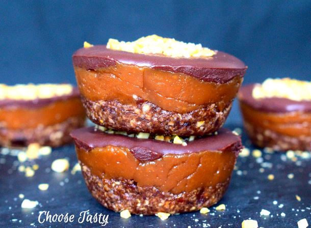 Banana peanut butter cups topped with chocolate glaze and roasted peanuts